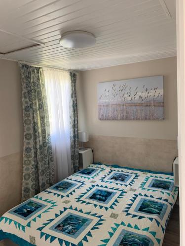 a bedroom with a bed with a quilt on it at TópART Apartman B Little House in Balatonfenyves