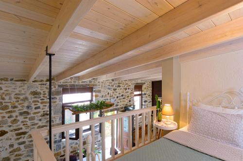 Cette chambre dispose d'un balcon avec un lit et un mur en pierre. dans l'établissement Platipodi stone house, à Nikithianós