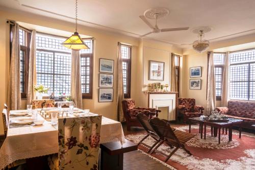 a living room with a table and chairs and a living room at StayVista at Raas Villa with BBQ & Bonfire in Chail