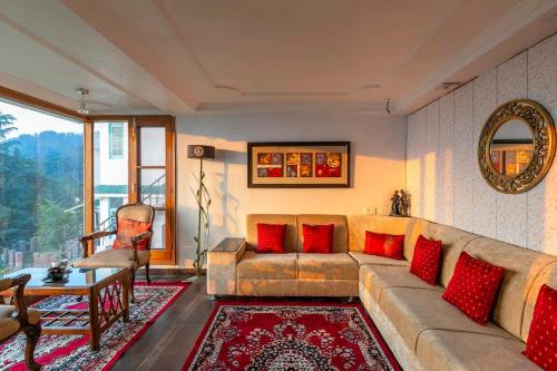 a living room with a couch and red pillows at StayVista at Raas Villa with BBQ & Bonfire in Chail