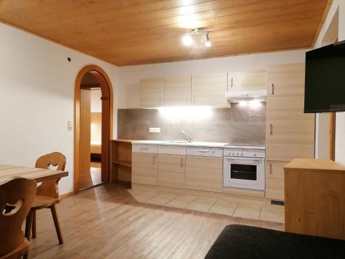 a kitchen with white cabinets and a table and a stove at Landhaus Brixental in Westendorf