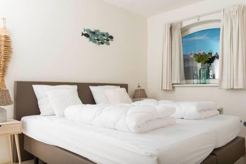 ein großes weißes Bett in einem Zimmer mit Fenster in der Unterkunft Residence Juliana 14 Julianadorp aan zee in Julianadorp