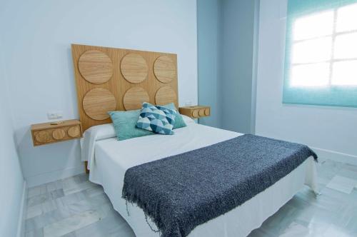 1 dormitorio con 1 cama grande y cabecero de madera en El Patio del Sol, apartamentos Living Sur, en Sanlúcar de Barrameda
