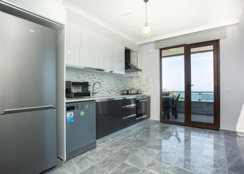 トラブゾンにあるGazioğlu Residenceのキッチン(ステンレス製の電化製品付)、大きな窓が備わります。