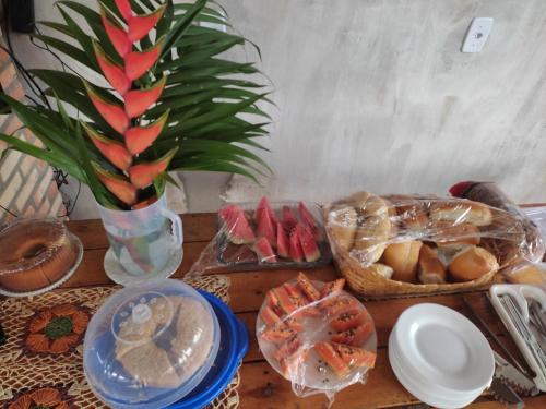 une table en bois avec de la nourriture et un vase contenant un ananas dans l'établissement Pousada RIOSTOUR, à Barreirinhas