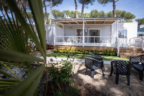 ein Haus mit einer Veranda mit Stühlen und Bäumen in der Unterkunft Anxur Village Camping in Terracina