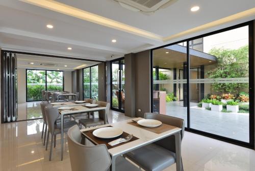 a dining room with tables and chairs and large windows at Grand BS Airport Hotel Suvarnabhumi in Lat Krabang