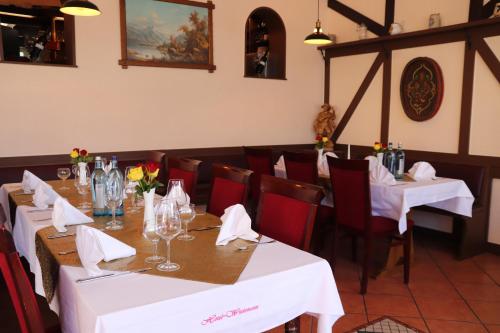 Hotel Weinhaus Wiedemann في غينشيم غوستافبرغ: غرفة طعام مع طاولات بيضاء وكراسي حمراء