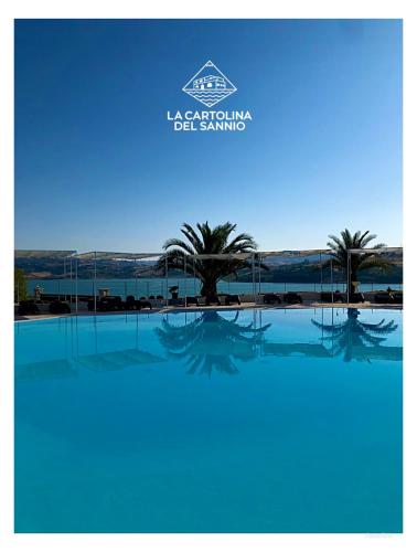 a picture of a swimming pool with palm trees at La Cartolina del Sannio in Campolattaro