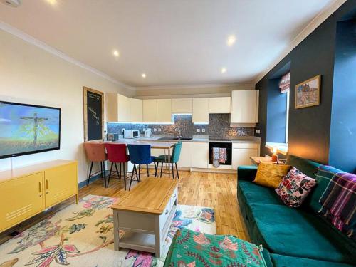 a living room with a green couch and a kitchen at Lively & Energetic 2BR on The Royal Mile in Edinburgh