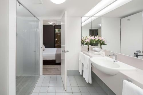 a white bathroom with a sink and a shower at Rydges Esplanade Resort Cairns in Cairns