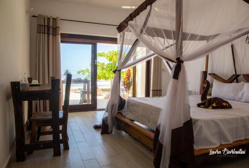 una camera con letto a baldacchino e finestra di Uroa Zanzibar Vera Beach Hotel by Moonshine a Dikoni