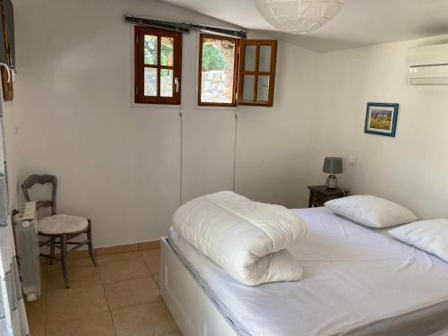 a bedroom with a bed with white sheets and a chair at Gîte Encore Un Soir in Hyères