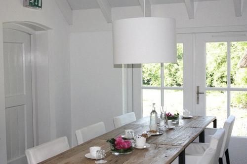een eettafel met witte stoelen en een grote lamp bij B&B Buitenplaats Natuurlijk Goed in Oosterwolde