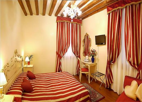 a bedroom with a bed and a desk and curtains at Hotel San Luca Venezia in Venice