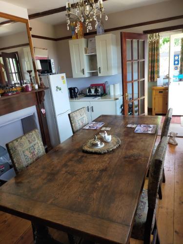 een keuken met een houten tafel met stoelen eromheen bij Meadow Farm Cottage in Norwich