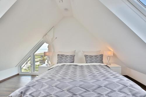 a white bedroom with a bed and a large window at Haus Meeresrauschen Haus Meeresrauschen Appartement 1 6 in Haffkrug