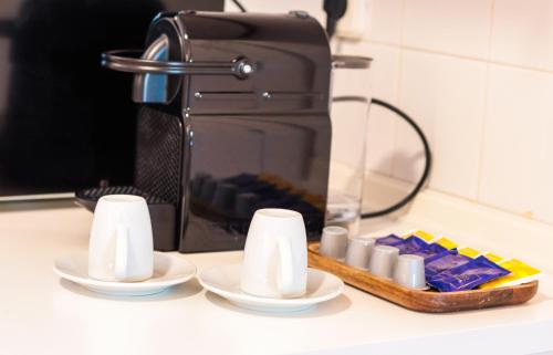 a counter top with two cups and a coffee maker at The Residences at Bairro Alto in Lisbon