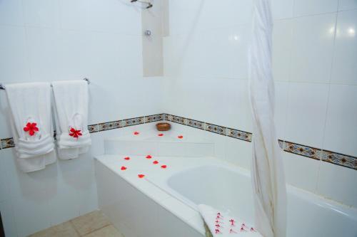 ein weißes Badezimmer mit einer Badewanne mit roten Blumen darauf in der Unterkunft Coconut Grove Regency Hotel in Accra