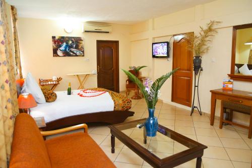a hotel room with a bed and a couch and a table at Coconut Grove Regency Hotel in Accra