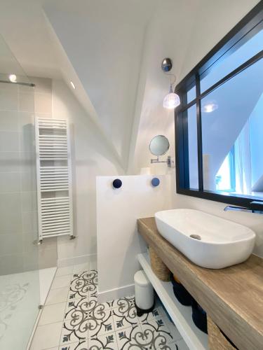 une salle de bain blanche avec un lavabo et une fenêtre dans l'établissement Superbe villa vue sur mer, corniche de la plage, à Bénodet