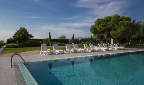 uma fila de espreguiçadeiras brancas junto a uma piscina em The Marmara Antalya em Antalya