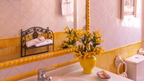 un baño con un jarrón amarillo con flores en un fregadero en Casa San Ignacio Cantillana by Ruralidays, en Sevilla