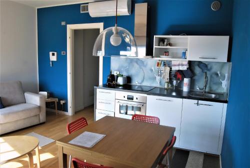 a kitchen with a table and a blue wall at MODERN & BRIGHT flat - 2 MIN from the SEA in Savona
