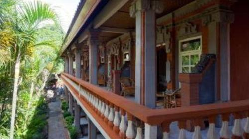 a porch of a house with a palm tree at Hotel Chonos in Lovina