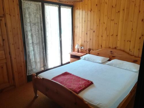 a bedroom with a bed with white sheets and a pink pillow at Appartamenti Abetaia in Dimaro