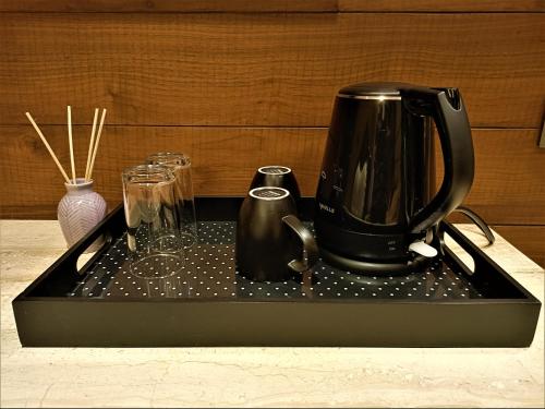 a black coffee maker sitting on a tray with glasses at Retrieve Health & Wellness in Cochin
