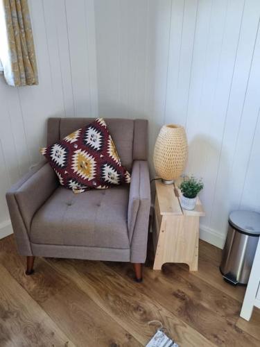 a living room with a couch and a table with a lamp at Shepherds Hut at Cummins Farm, Lyme Regis in Bridport