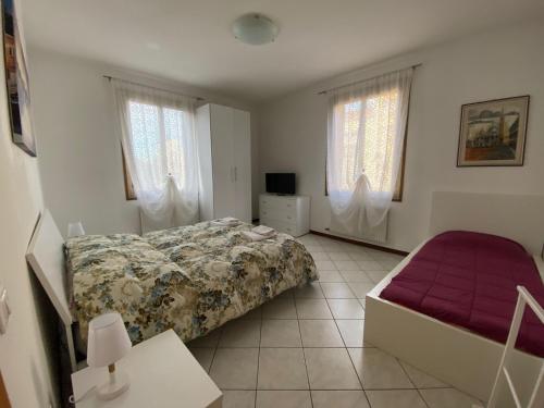 a bedroom with a bed and a couch and windows at Little and cozy flat near Venice in Marghera