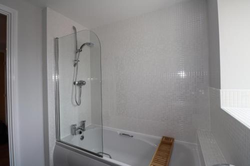 ein weißes Bad mit einer Badewanne und einer Dusche in der Unterkunft Millplace Apartments Derby in Derby