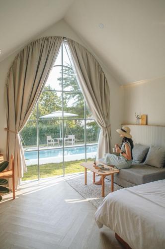 a person sitting on a couch in a room with a window at La Kana Boutique Villa in Kamphaeng Phet