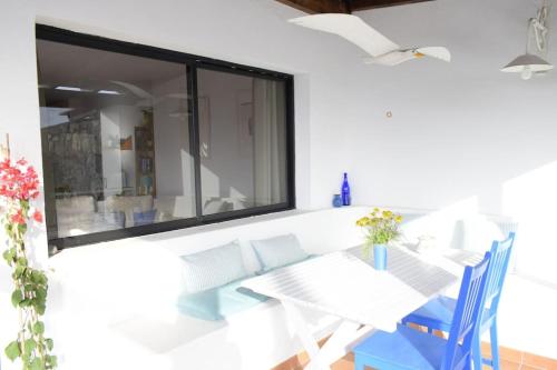 a dining room with a white table and blue chairs at Casa SocAire. Naturaleza, mar, paz, relax. in Tabayesco