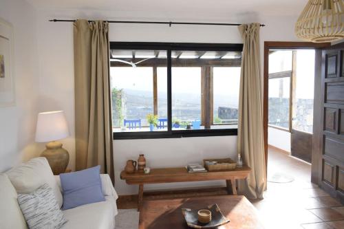 ein Wohnzimmer mit einem Sofa und einem großen Fenster in der Unterkunft Casa SocAire. Naturaleza, mar, paz, relax. in Tabayesco