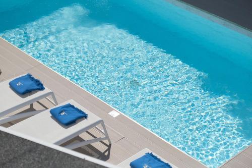 an overhead view of a swimming pool with two blue chairs at Porto Vecchio Luxury Suites in Spetses