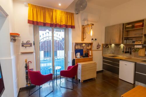 a kitchen with red chairs and a table and a window at Alba Chiara in Acitrezza