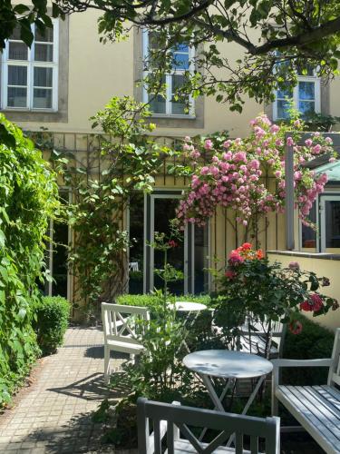 a patio with two white benches and pink flowers at Hofgärtnerhaus in Dresden