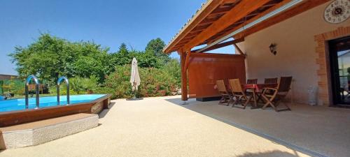 une terrasse avec une piscine, une table et des chaises dans l'établissement Les Terrasses de L'Oliu de L'Oustalet, à Castelsarrasin