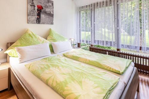 1 dormitorio con 1 cama con sábanas verdes y blancas en Ferienwohnung Fetscher 1, en Reichenau