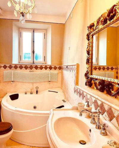 a bathroom with a tub and a sink and a mirror at Palazzo Barbini Dimora Storica in Castiglione del Lago