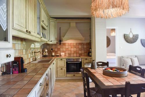 a kitchen with wooden cabinets and a table with a bowl of fruit at Charming House in Armentistis, Ikaria in Armenistis
