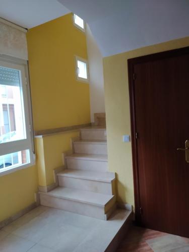 a staircase in a room with yellow walls and a door at Chalet adosado con azotea andaluza y patio, junto a la playa in Isla Cristina