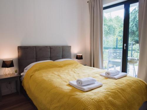 a bedroom with a yellow bed with towels on it at Apartament Nad Strumykiem z ogródkiem - Dream Apart in Ustroń
