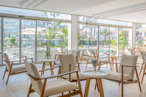 una stanza con tavoli, sedie e finestre di Helios Mallorca Hotel & Apartments a Can Pastilla