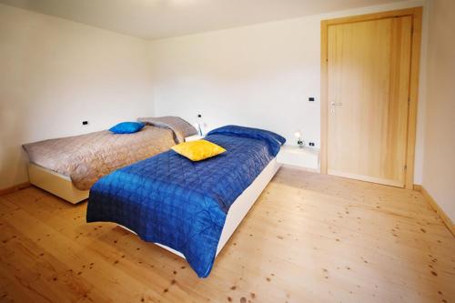 a bedroom with a bed with a blue comforter and yellow pillows at La Marmote Albergo Diffuso di Paluzza Aip in Paluzza