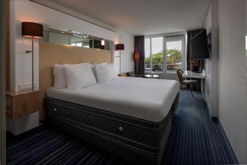 ein Hotelzimmer mit einem großen Bett und einem Schreibtisch in der Unterkunft WestCord Hotel de Wadden in Oost-Vlieland