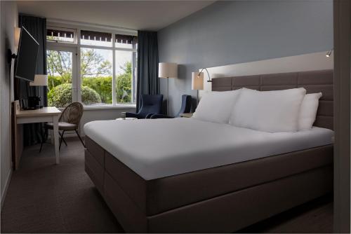 Cette chambre comprend un lit, un bureau et une fenêtre. dans l'établissement WestCord Hotel de Wadden, à Oost-Vlieland